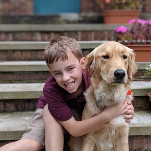 A young boy and his Therapy dog sitting on front steps of a residential building