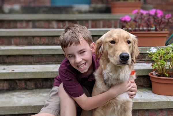 A young boy and his Therapy dog sitting on front steps of a residential building