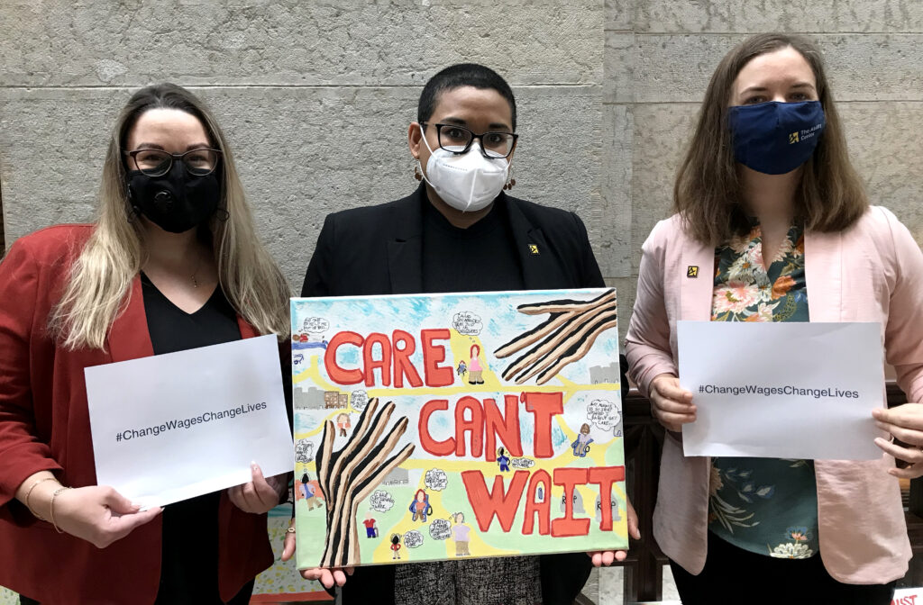 Brittanie Maddox, Vera Mendoza, and Katie Hunt Thomas holding signs that say "Care Can't Wait" and "Change wages, change lives."